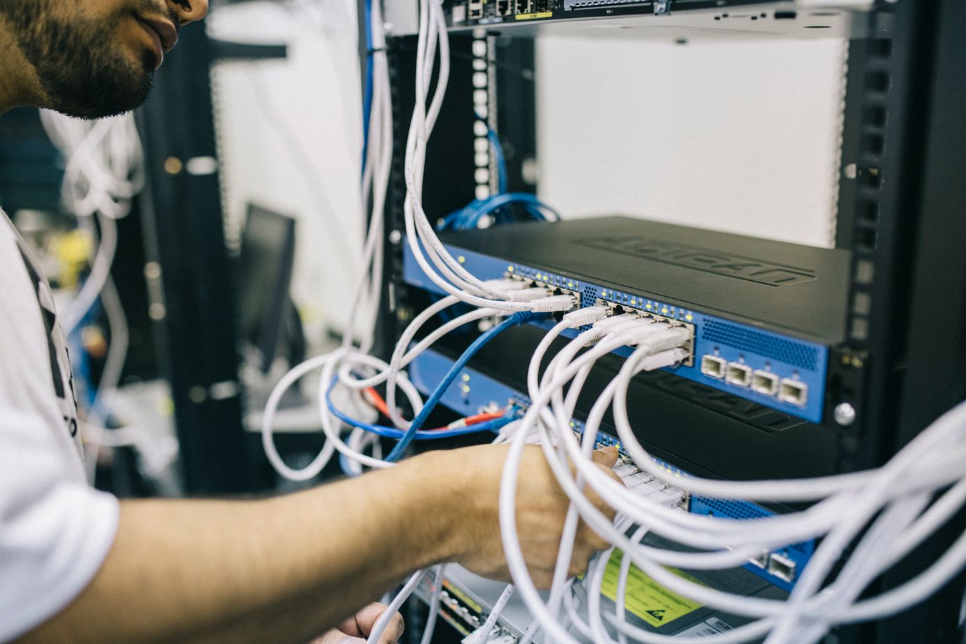 A technician's hands working through the cables in a network rack